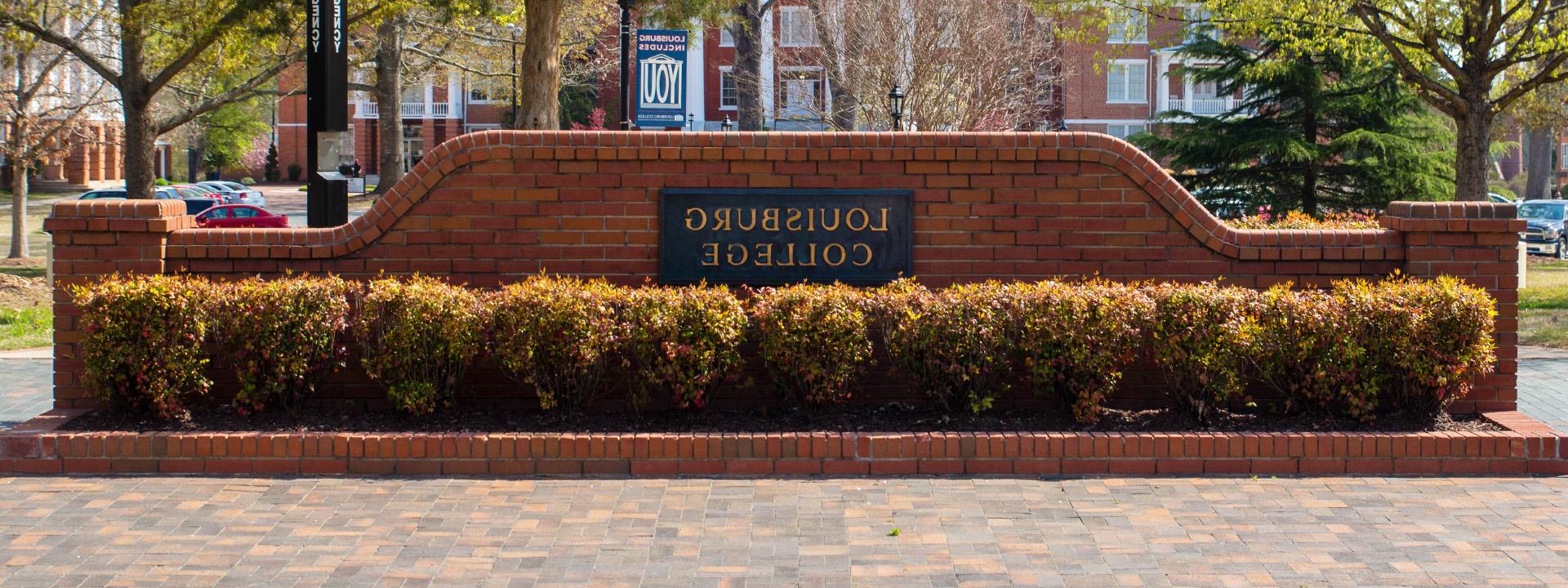 a brick wall on campus that reads Louisburg College